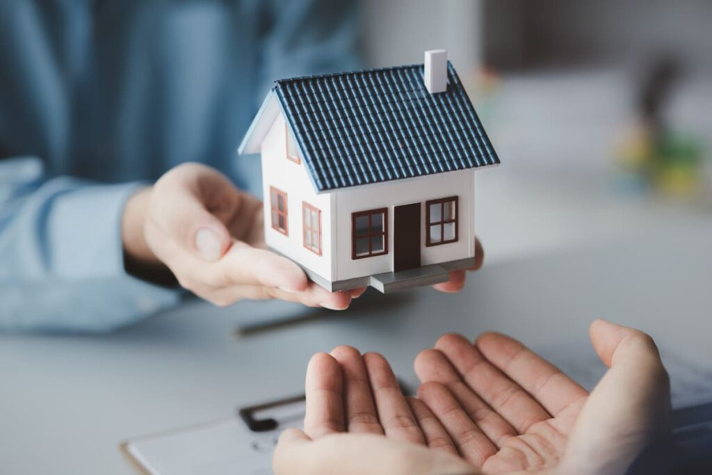 manos manos sosteniendo una maqueta de una casa de seguro de hogara para explicar qué seguros se puden desgravar en la renta