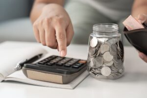 mujer calculando qué seguros se pueden desgravar en la renta con una calculadora y una hucha