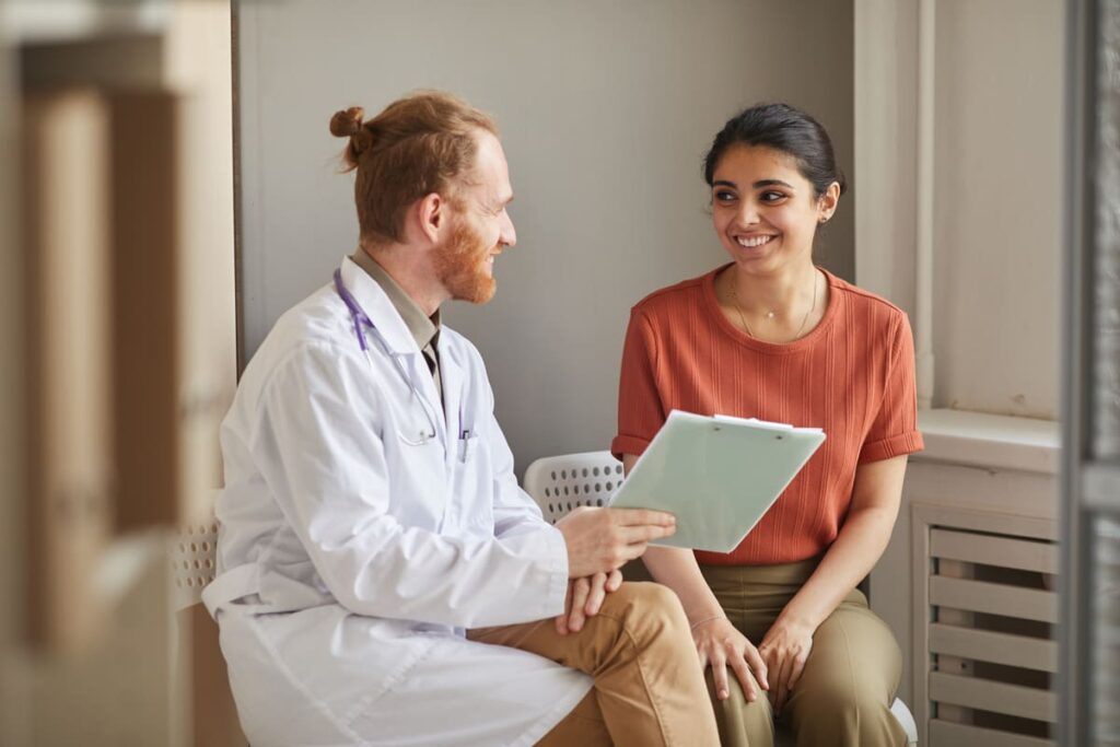 un médico y una mujer hablando tranquilamente sobre contratar seguro de salud