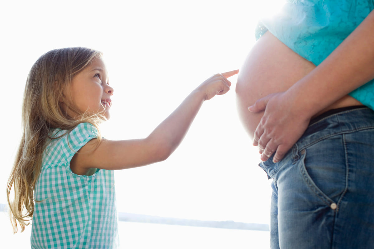 una niña tocando la barriga a una embarazada preguntándose cómo se tienen hijos