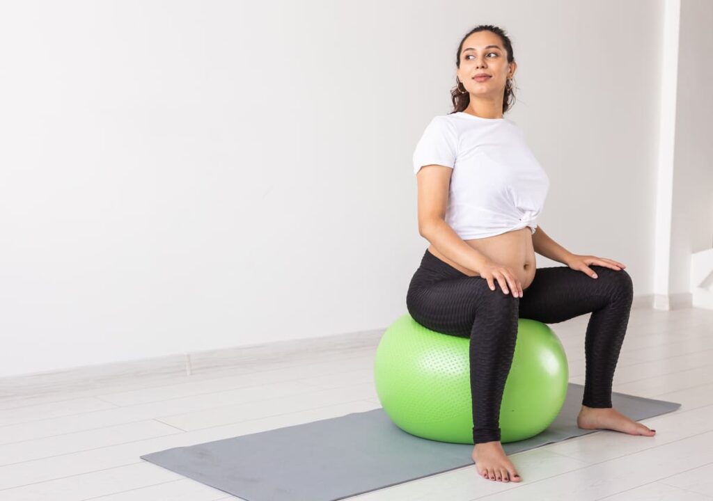 mujer embarazada sentada en una pelota hinchable aprendiendo los ejercicios suelo pélvico post parto