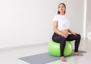 mujer embarazada sentada en una pelota hinchable aprendiendo los ejercicios suelo pélvico post parto